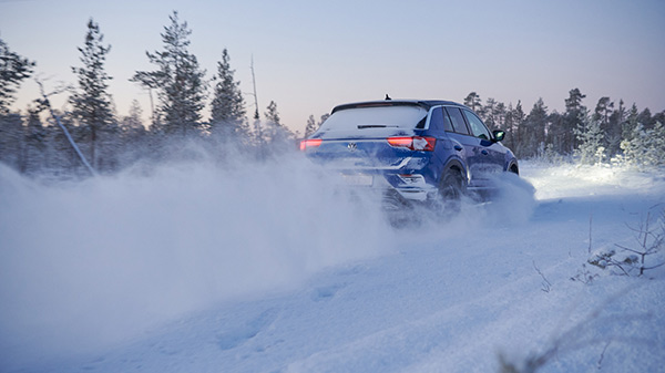 Voiture en train de rouler sur une route enneigée.